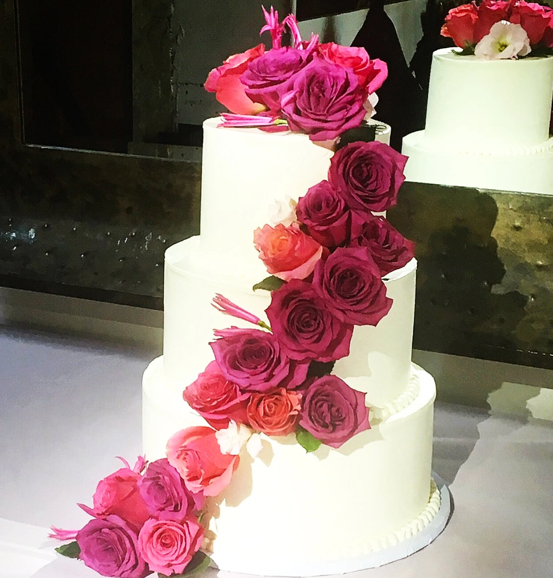 Custom Three-Teired Wedding Cake from Bella Bakery with Row of Flowers